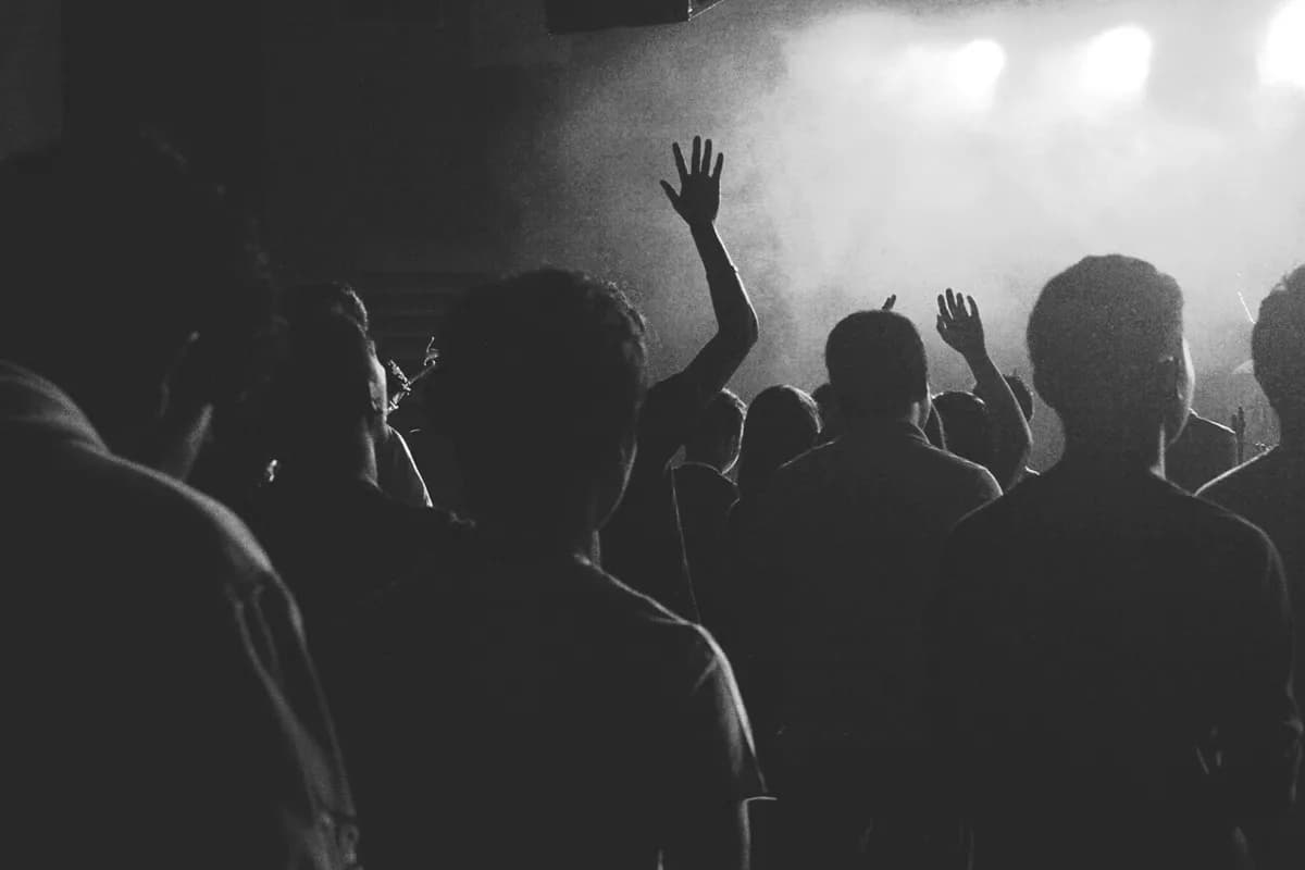 A crowd with raised hands in front of a concert stage