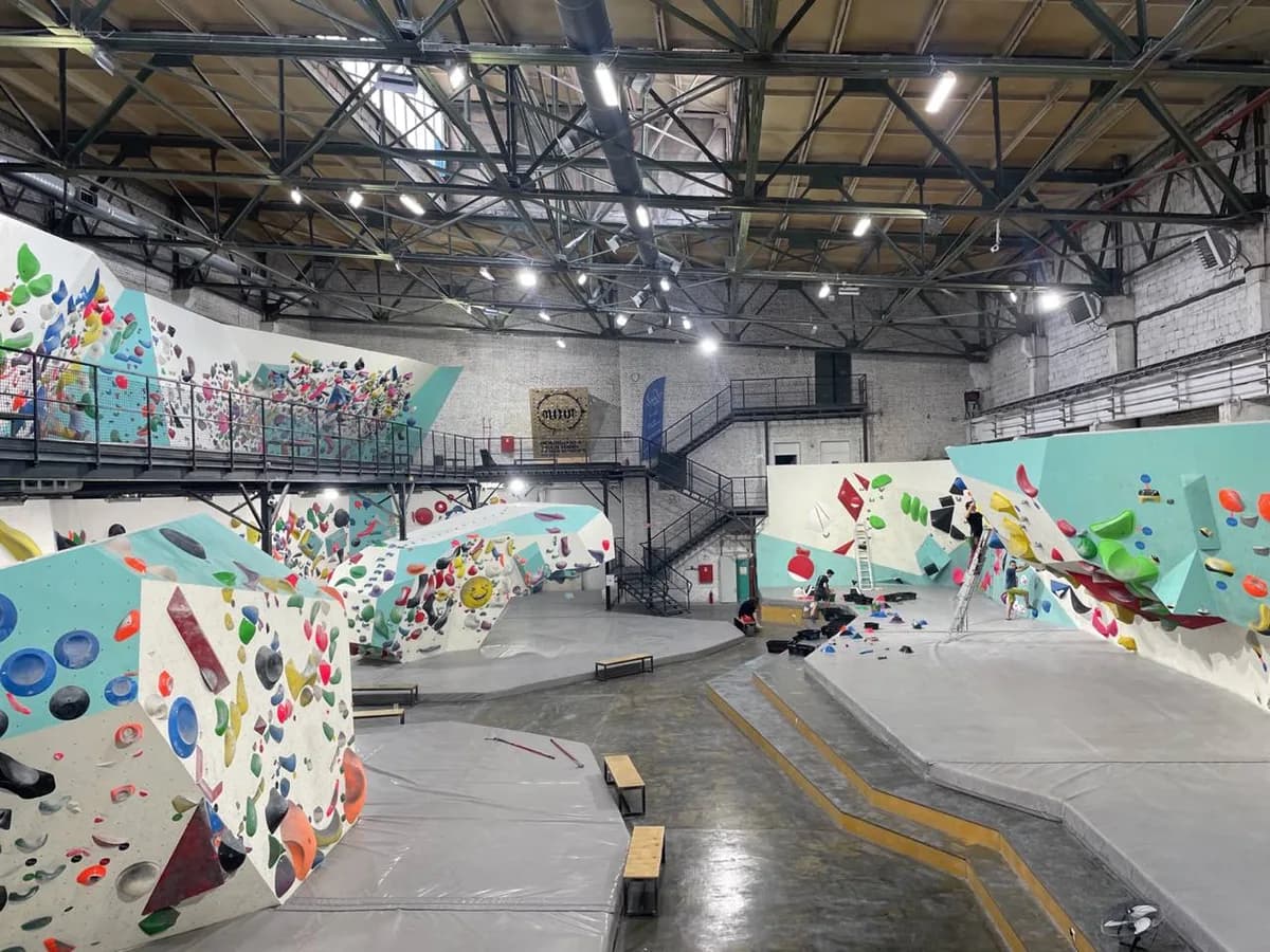 An indoor bouldering gym with colourful holds on angled walls